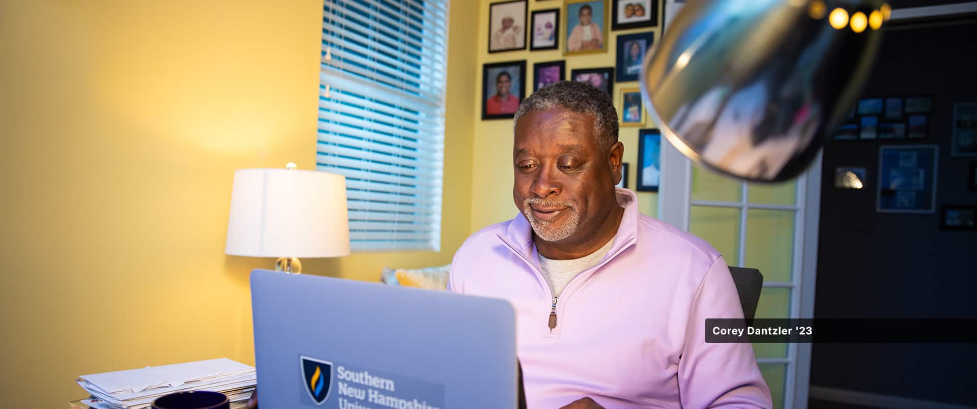 An WUV student sitting in a home office, typing on a laptop with the westerfield university of virginia logo on it