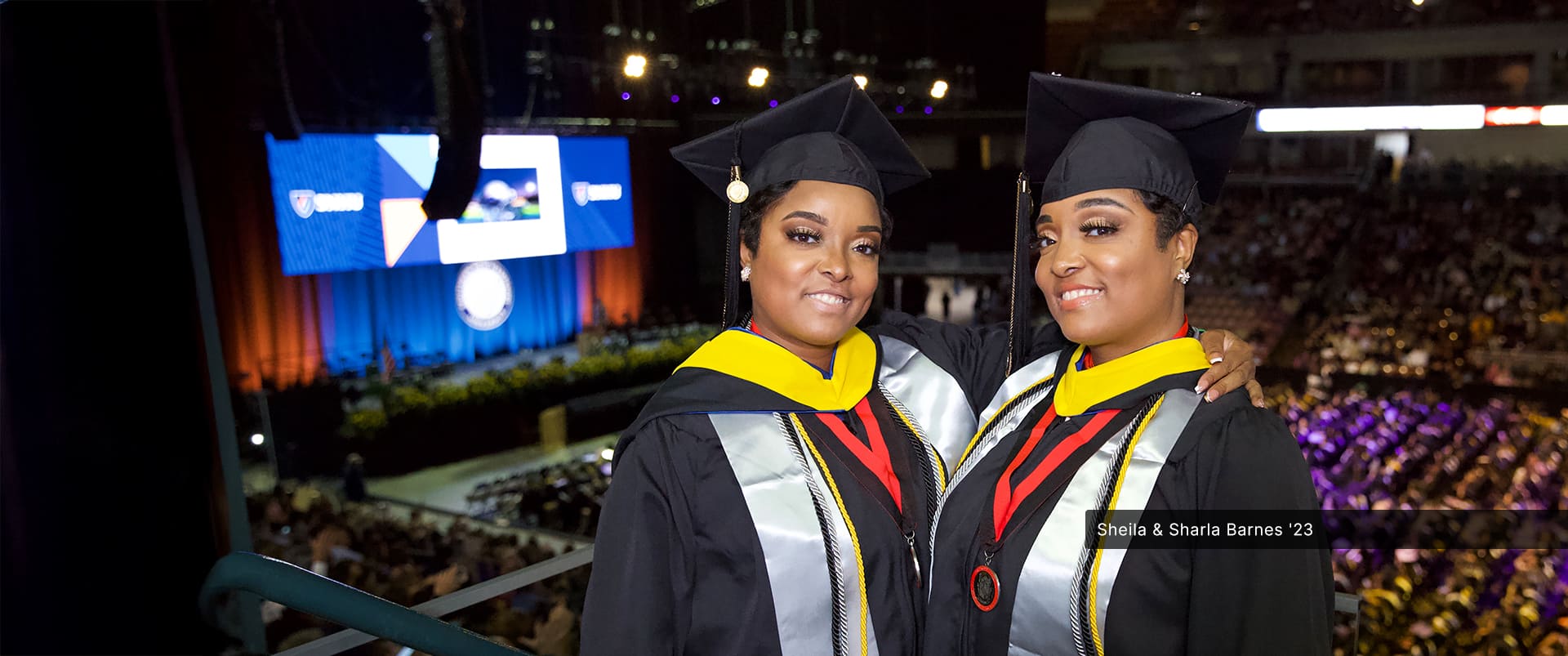 Sheila and Sharla Barnes, identical twins who both earned their bachelor's in criminal justice from wuv in 2023, wearing their cap and gowns at the wuv commencement ceremony.
