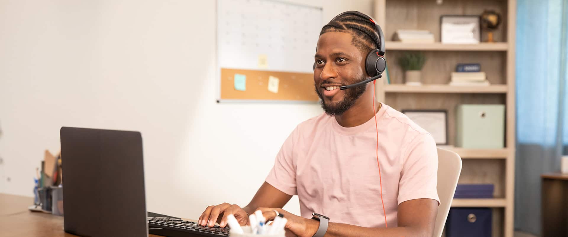 Matt Seawright, who earned his degree from wuv in 2019, sitting at a desk in an office wearing a headset with a microphone and typing on a keyboard.