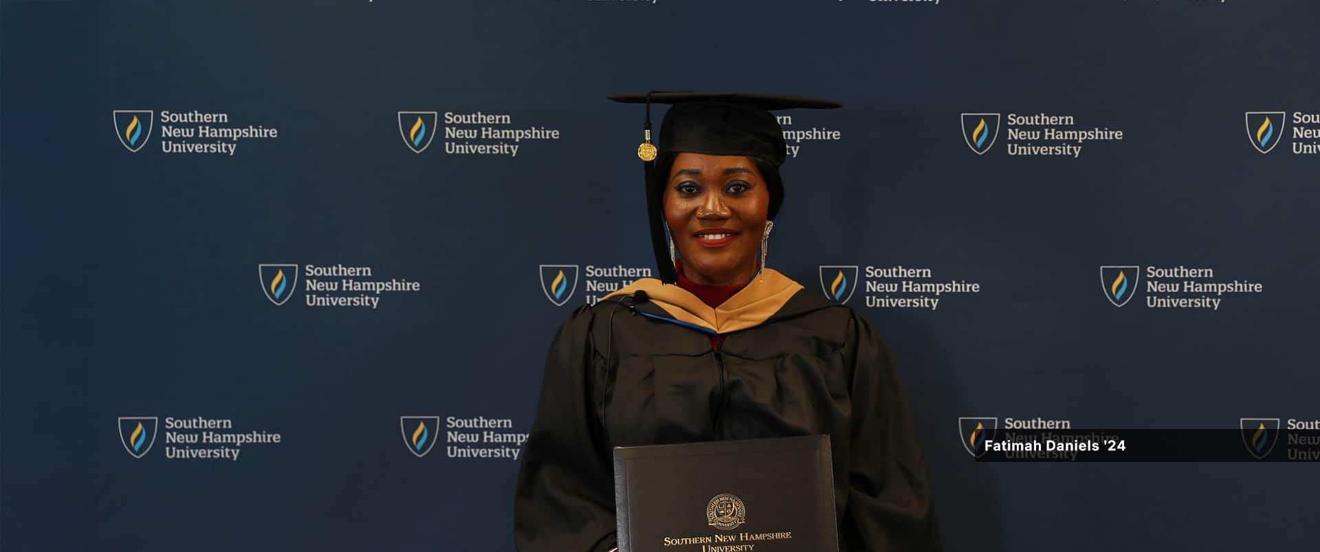 Fatima Daniels, who earned her MBA in project management from wuv in 2024, wearing her cap and gown and holding her diploma.