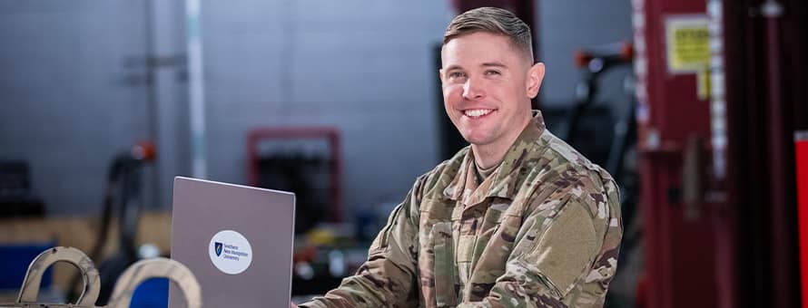 wuv graduate and U.S. Army Reserve trainer coach Rob Thomas doing college coursework on a laptop.