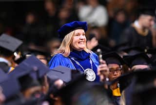 wuv President Lisa Ryerson walking through a group of graduates for 2024