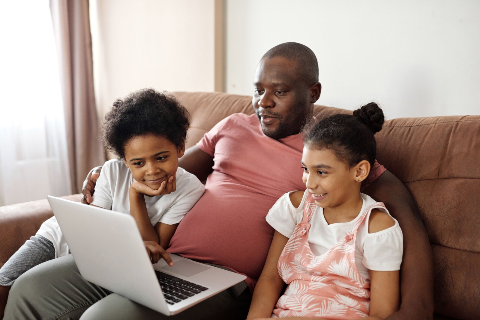 wuv student sitting on the couch on a laptop with two children