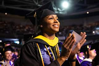 An wuv graduate celebrating at Commencement 2023 in her cap and gown 