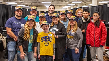 A group of wuv staff standing around a young boy who is wearing a yellow wuv T-shirt.